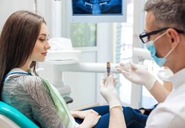 Dentist showing female patient a dental implant model