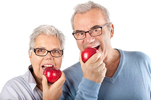 Senior man and woman eating red apples